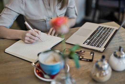 a person writing in a notebook at a quiet café